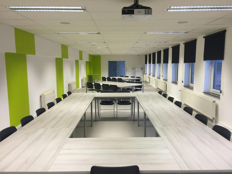 Spacious indoor meeting room with modern furniture and large windows.